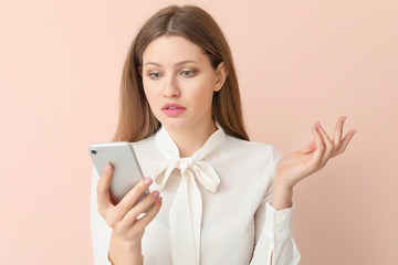 Sad businesswoman with mobile phone on color background
