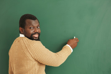 African-American teacher writing on blackboard in classroom