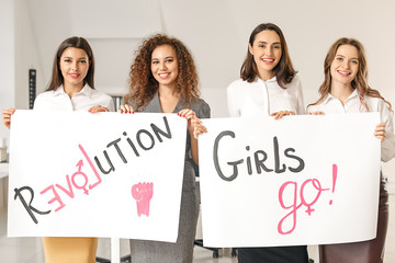 Young women with posters in office. Concept of feminism