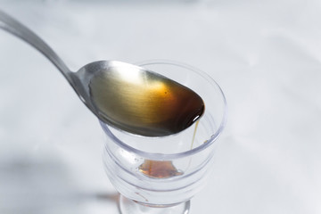 Female hand pouring a table spoon of honey into a glass