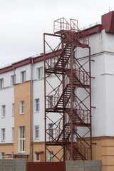 Fototapeta na wymiar Fire Escape, red metal staircase, emergency exit on side of building 