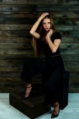 The concept of glamor, style. The model sits in different poses on an alternative stand in front of the camera. Portrait of a pretty blonde girl with long hair and great makeup on a wooden background.