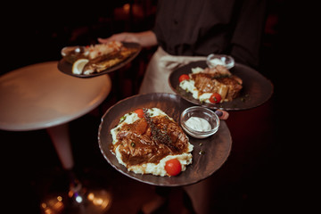 the waiter is holding a beef steak with mashed potatoes