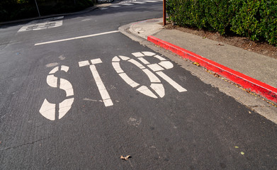 Obraz premium Stop sign painted on asphalt of red curb street at intersection