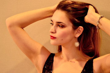 Beautiful young spectacular girl in a shiny black dress with an open neckline 