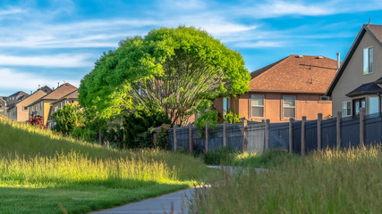 Panorama Views at a golf course with paved road and grasses near homes with metal fences