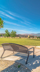 Fototapeta na wymiar Vertical Park metal bench with view of lake snowy timpanogos mountains and blue sky