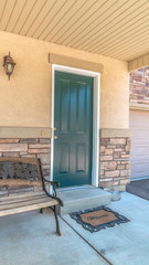 Vertical frame Old porch bench against stone brick wall of home with green wood front door