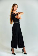 Fototapeta premium Full-length portrait of a pretty blonde girl with long hair and excellent make-up on a white background. Model student manager stands in different poses in front of the camera in the studio.