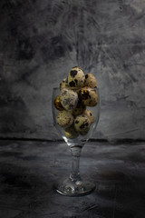 Quail eggs in the glass on dark background