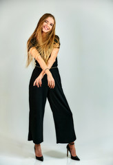 Model student manager stands in different poses in front of the camera in the studio. Full-length portrait of a pretty blonde girl with long hair and excellent make-up on a white background.