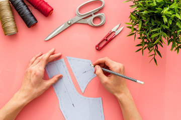 Tailor working. Women hands drawing patterns for clothes on pink background top-down