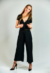 Model student manager stands in different poses in front of the camera in the studio. Full-length portrait of a pretty blonde girl with long hair and excellent make-up on a white background.