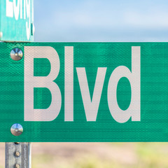 Square frame Selective focus on a green and white road street sign that reads Blvd