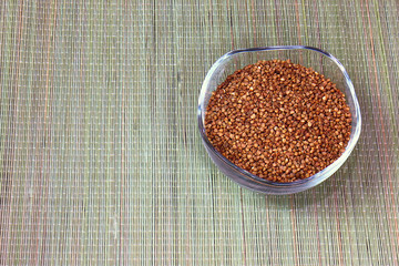 buckwheat groats in a glass cup standing on a straw mat