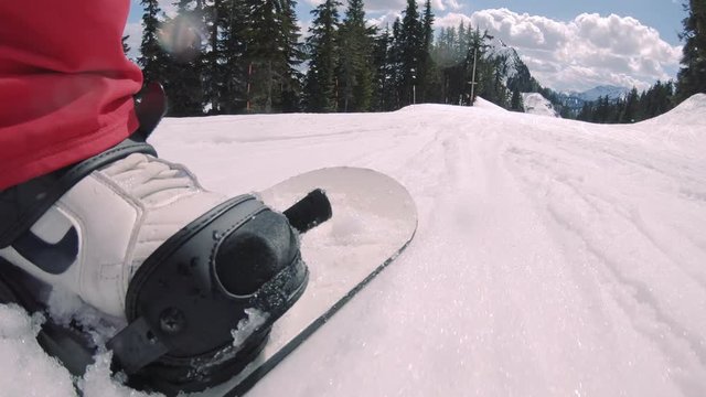 Pan from Man Wearing Beanie and Goggles to Snowboard Riding Resort Run
