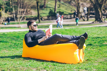 book reading concept. man in city park on inflatable mattress