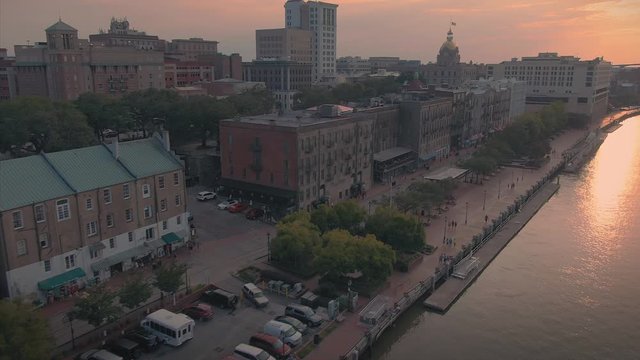 Aerial: Establishing shot of the riverfront of Savannah and historical buildings at sunset. Savannah, Georgia,