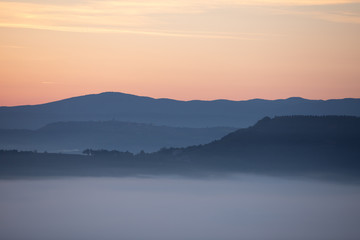 view of sunrise over the mountains mist and clouds under peaks