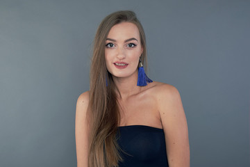 Fototapeta premium Woman with beauty long brown hair, posing at studio. long earrings classic blue