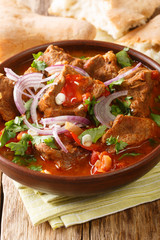 Chashushuli is a delicious Georgina beef stew with tomato and spices close-up in a bowl. vertical
