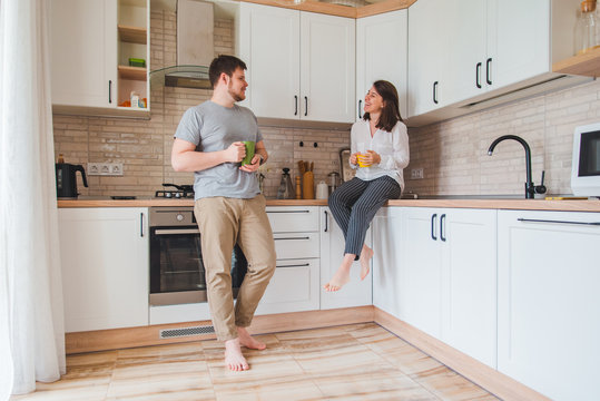smiling man with woman at kitchen drinking tea