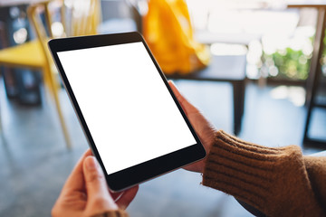 Mockup image of a woman sitting and holding black tablet pc with blank white desktop screen