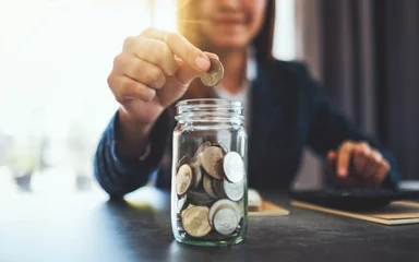 Foto op Aluminium Closeup image of a businesswoman collecting and putting coins in a glass jar © Farknot Architect