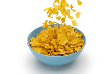 Motion blur of pouring golden cornflakes flowing into the blue bowl isolated on white background