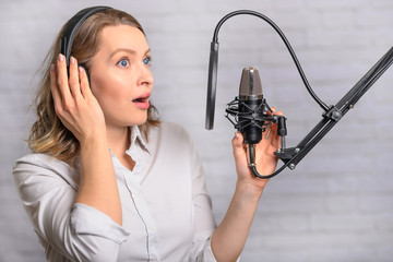 Emotional reading a girl news on the radio, in the studio with a studio microphone. Podcasts,...