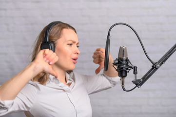 A girl works with a microphone, recordings Audio recording on the radio, or dubbing an audiobook,...
