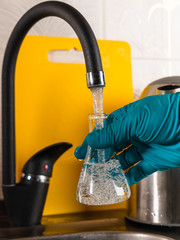 A specialist pours tap water into a glass flask.
