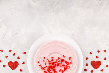 Valentine Background with Two Plates with Red Glass Branches and Paper Glitter Hearts Confetti on Concrete Background. Concept of Happy Valentines Day. Top View, Copy Space, Flat Lay