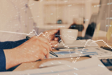 Double exposure of man's hands writing notes of stock market with forex graph.
