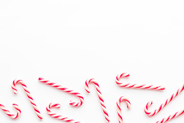 Christmas candies frame - cane with red and white stripes - on white background top-down copy space