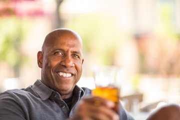Mature African American man drinking at a restaurant.