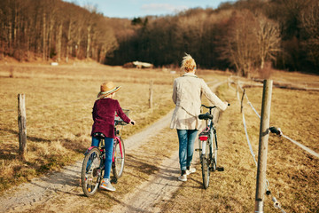 Fototapeta premium Mother and daughter with bicycles on countryside.
