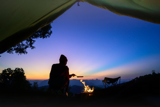 Silhouette Of Woman Traveller Camping In Campsite With Cooking Meal Dinner