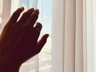 Silhouette of a girl while waking up in the room and holding curtain.