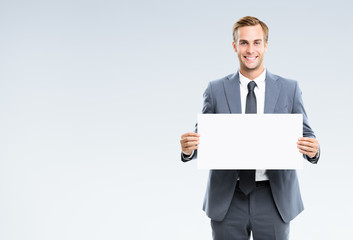 Businessman in grey confident suit, showing blank signboard. Empty copy space for some slogan or...