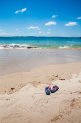 Asutralia Day and immigration concept background: patriotic Aussie thongs featuring Australian flag on the beautiful sandy beach beach.