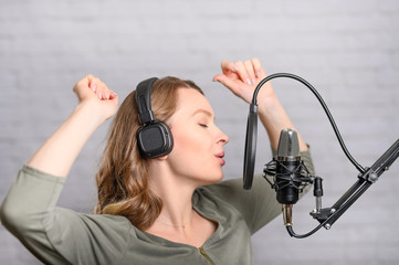 Female vocal recording. Young girl with microphone and headphones in recording studio. Recording of...