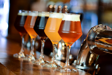 Three glasses with different beer on wooden table in a bar. Food photography concept, with copy space