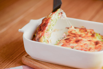 Classic lasagna with bolognese sauce, with cheese layered between sheets served in a white plate on a wooden background