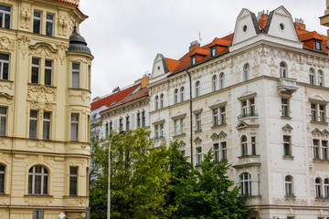 Fototapeta premium Facade of typical colorful czech houses with trees at the foreground in Prague, Czech Republic