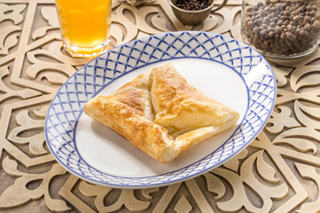 Traditional Georgian khachapuri pie with cheese and glass of yellow drink on oriental wooden table