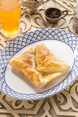 Traditional Georgian khachapuri pie with cheese and glass of yellow drink on oriental wooden table
