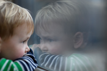 Little boy looking through window. He travels on a train.
