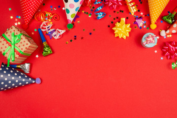 Festive golden and purple stars of confetti  and a present, birthday caps on a red background.
