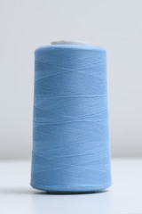 Spool of blue synthetic or cotton threads on white background. Spool of yarn using for weaving in textile manufacturing